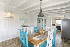 Cozy dining area with a wooden table and six chairs, surrounded by artwork and a decorative wreath.
