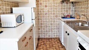 A compact kitchen with white cabinets, a microwave, a sink, and a stove. - Nice apartment for 2 guests with WIFI, TV, balcony and pets allowed (Narbonne)