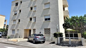 A multi-story building with a parking area and a car parked in front. - Nice apartment for 2 guests with WIFI, TV, balcony and pets allowed (Narbonne)