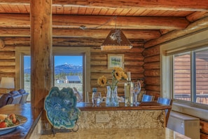 L’intérieur d’un chalet en bois comprend un comptoir de cuisine, un coin repas et offre une vue sur les montagnes.