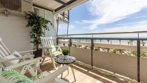A balcony with white chairs, a small table, and a potted plant. - Cosy apartment for 5 guests with A/C, WIFI, TV and balcony (Salou)