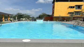 A swimming pool with a clear blue water surface, surrounded by a tiled deck.