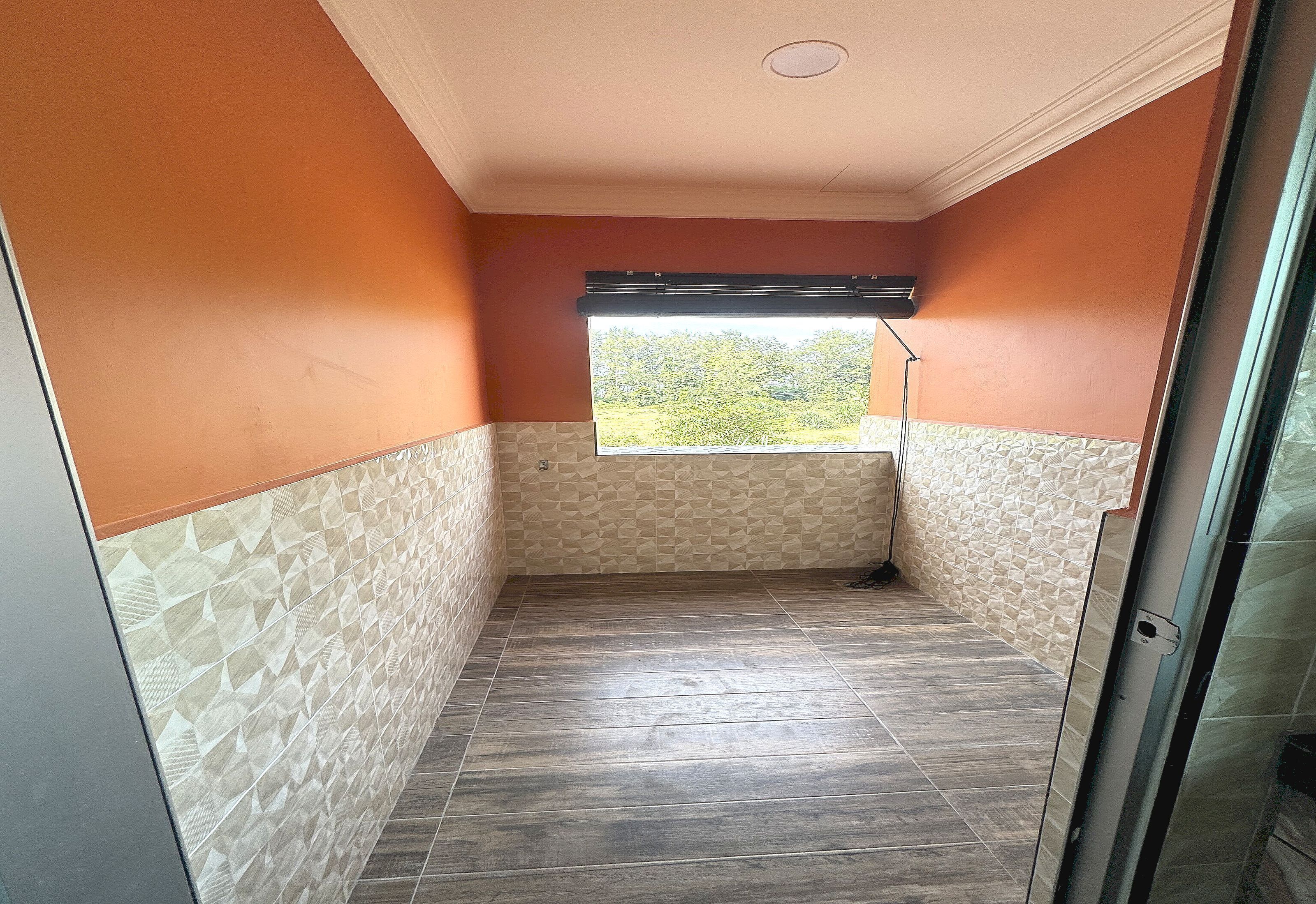 A room with a view through a window, a ceiling vent, and a patterned wall.