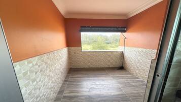 A room with a view through a window, a ceiling vent, and a patterned wall.