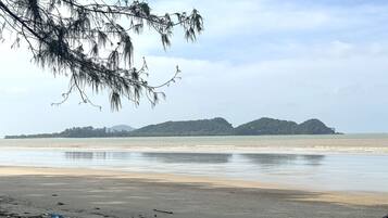 A beach with a sandy shore, a calm sea, and distant green hills.