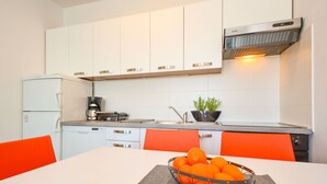 Eine moderne Küche mit weißen Schränken, einer Kaffeemaschine, einem Toaster und einer Schüssel Orangen auf der Arbeitsfläche.