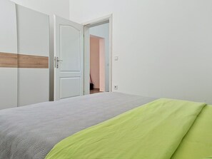 Une chambre à coucher avec un lit, une armoire et une porte ouverte donnant sur une autre pièce.