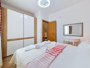 A hotel room with a bed, a bedside table, a mirror, a wardrobe, and a door leading to another room. - Cosy apartment for 4 people with A/C, WIFI, TV and terrace (Solin)