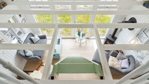 Une pièce spacieuse avec un plafond haut, de grandes fenêtres et une vue sur l’extérieur.