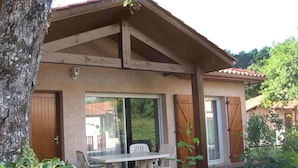 A covered outdoor seating area with a table and chairs, a wooden door, and a window. - Beautiful apartment for 4 guests with pool, WIFI, TV and terrace (Capbreton)
