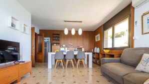 Une cuisine moderne avec des meubles en bois, un coin repas avec des chaises, un canapé et un téléviseur.