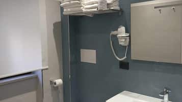 Une salle de bain équipée de toilettes, d’un lavabo, d’un porte-serviettes et d’un miroir.