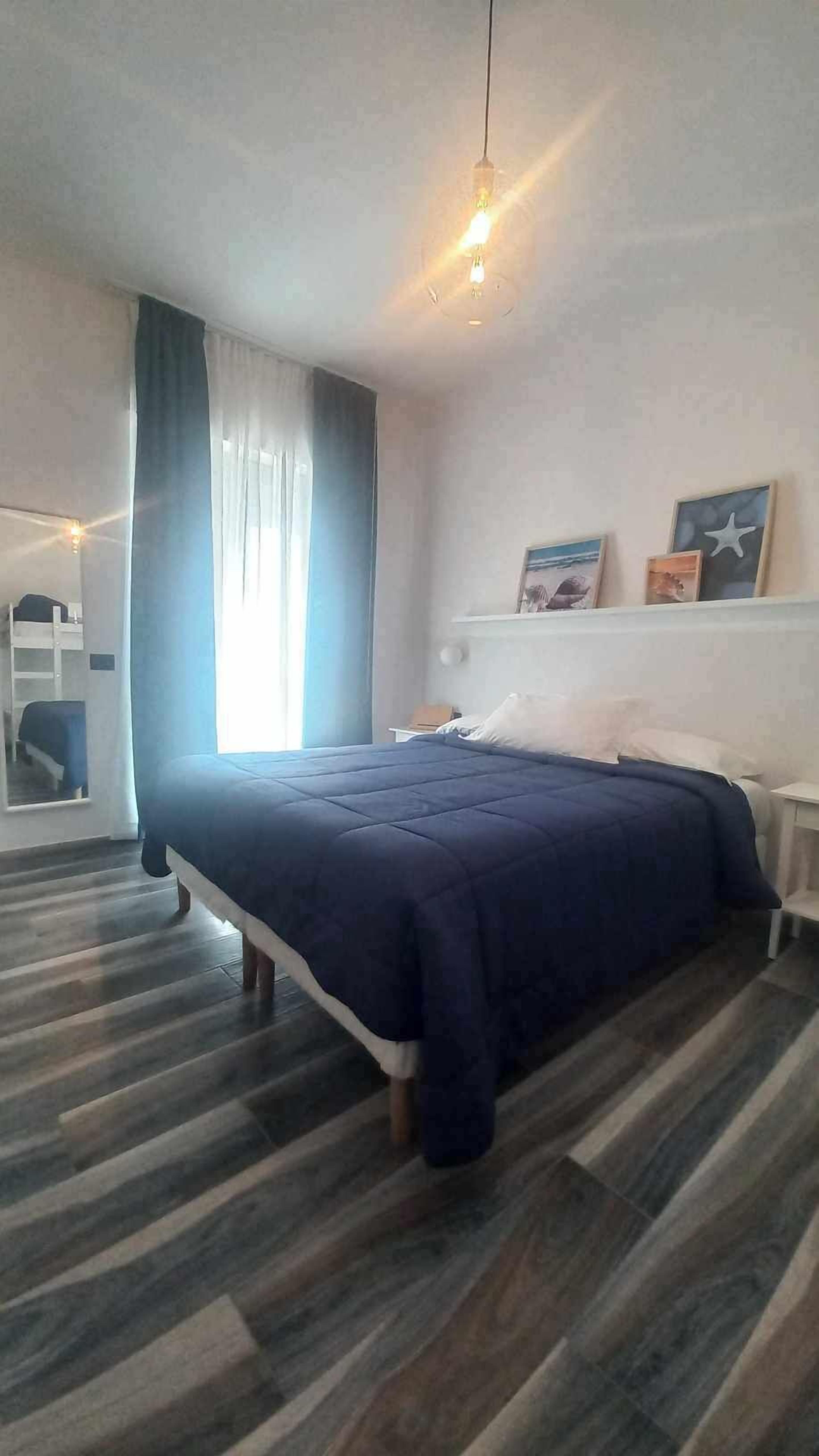 A bedroom with a bed, a nightstand, a dresser, and a window with curtains.
