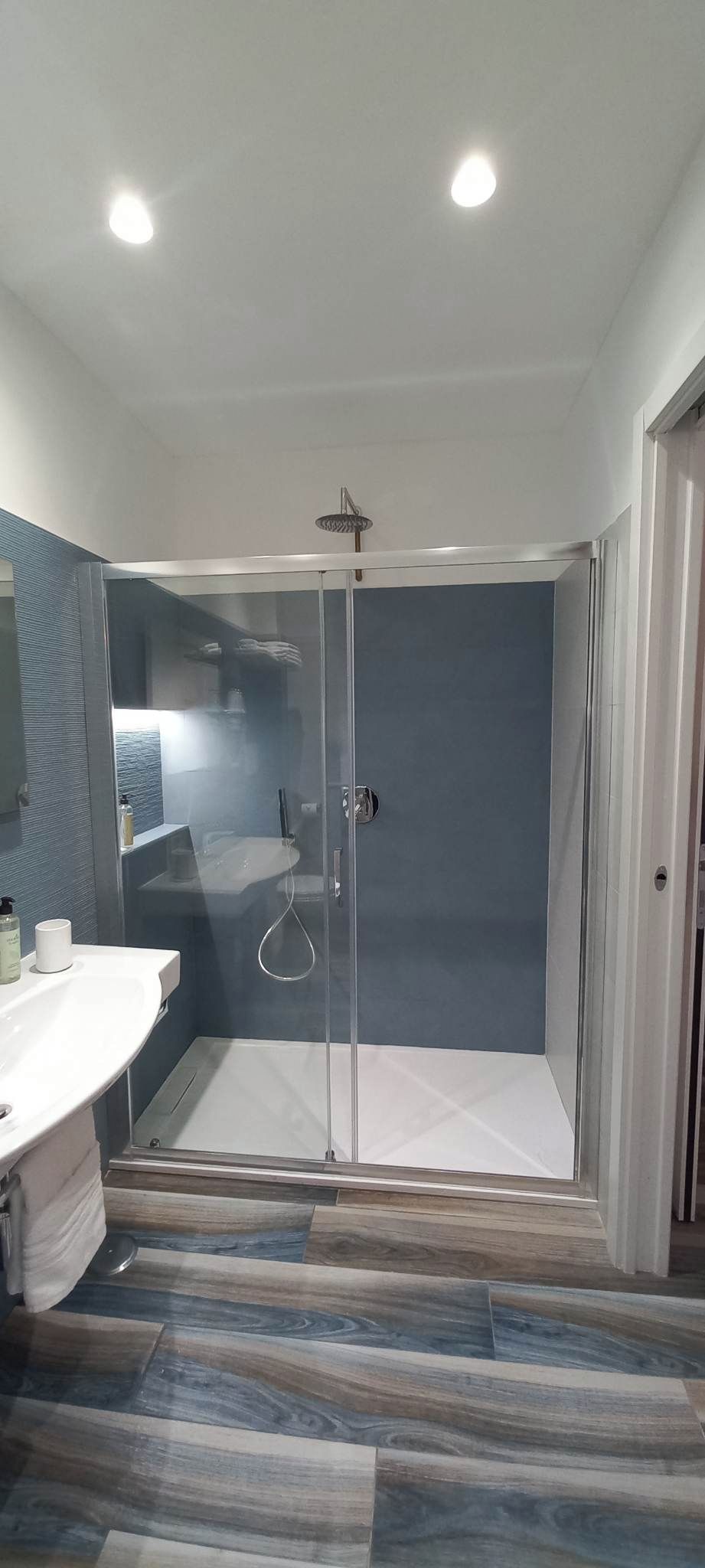 Un baño moderno con ducha acristalada, lavabo blanco y espejo.