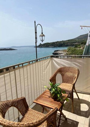 A balcony with wicker furniture, a table, and a potted plant. - B&B Fronte Mare (Camerota)