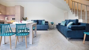 A modern living room with a sofa, chairs, a dining table, and a staircase. - Glikanisos House Nipos - Ideal for Hikers and Families 2bd, 6pl, 10min to Beach (Apokoronas)