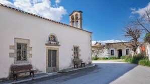 A building with a bell tower, a bench, and a mountain in the background. - Glikanisos House Nipos - Ideal for Hikers and Families 2bd, 6pl, 10min to Beach (Apokoronas)