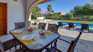 An outdoor dining area with a table set for two, overlooking a swimming pool and a garden. - Stunning private villa for 6 people with WIFI, A/C, private pool, TV, terrace and pets allowed (Teulada)