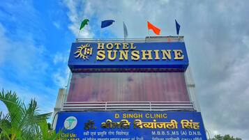 Un letrero de hotel con el nombre "HOTEL SUNSHINE" y un letrero de clínica debajo.