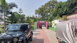 A paved pathway leading to a building with a red archway. - Hotel sunshine (Purnia)
