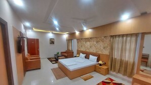 A modern hotel room with a large bed, a sofa, a small table, and a TV. - Hotel sunshine (Purnia)