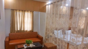 A living room with a sofa, a coffee table with a plant, and a small ottoman. - Hotel sunshine (Purnia)
