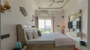 Une chambre moderne avec un grand lit, une télévision et une vue sur l’extérieur.