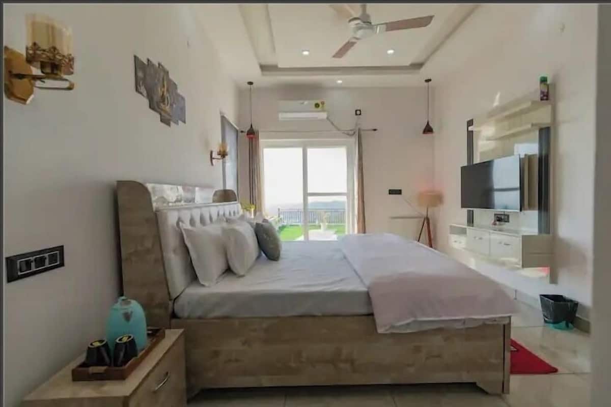 Un dormitorio moderno con una cama grande, un televisor y vistas al exterior.