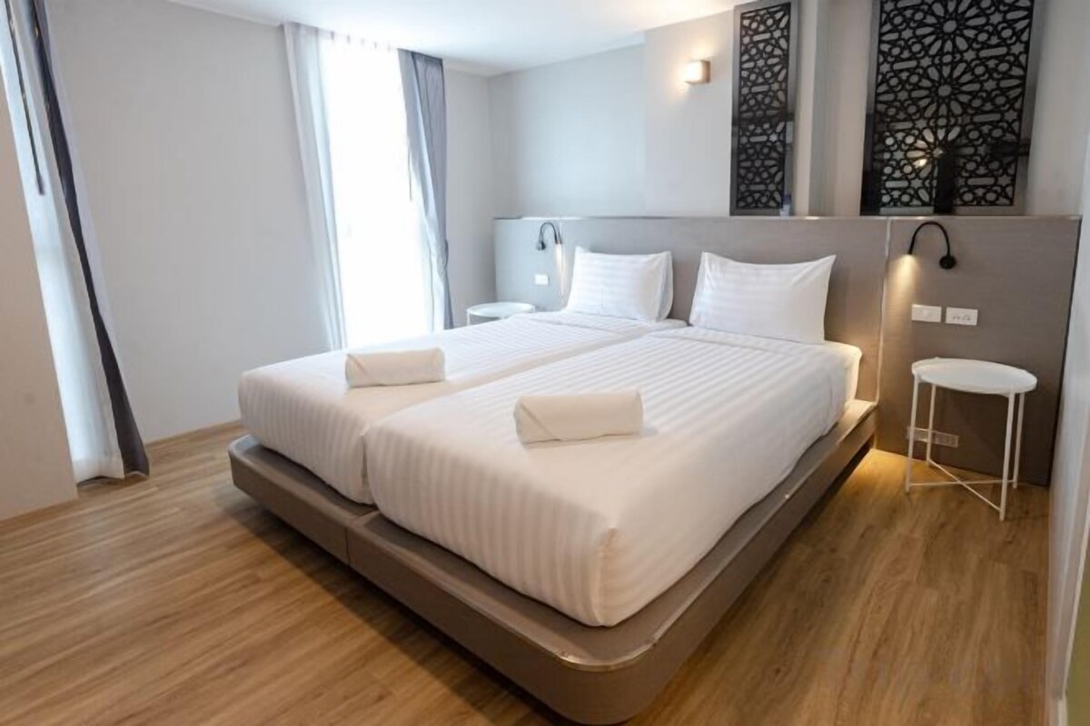 Habitación de hotel moderna con una cama grande, mesitas de noche y un panel decorativo en la pared.