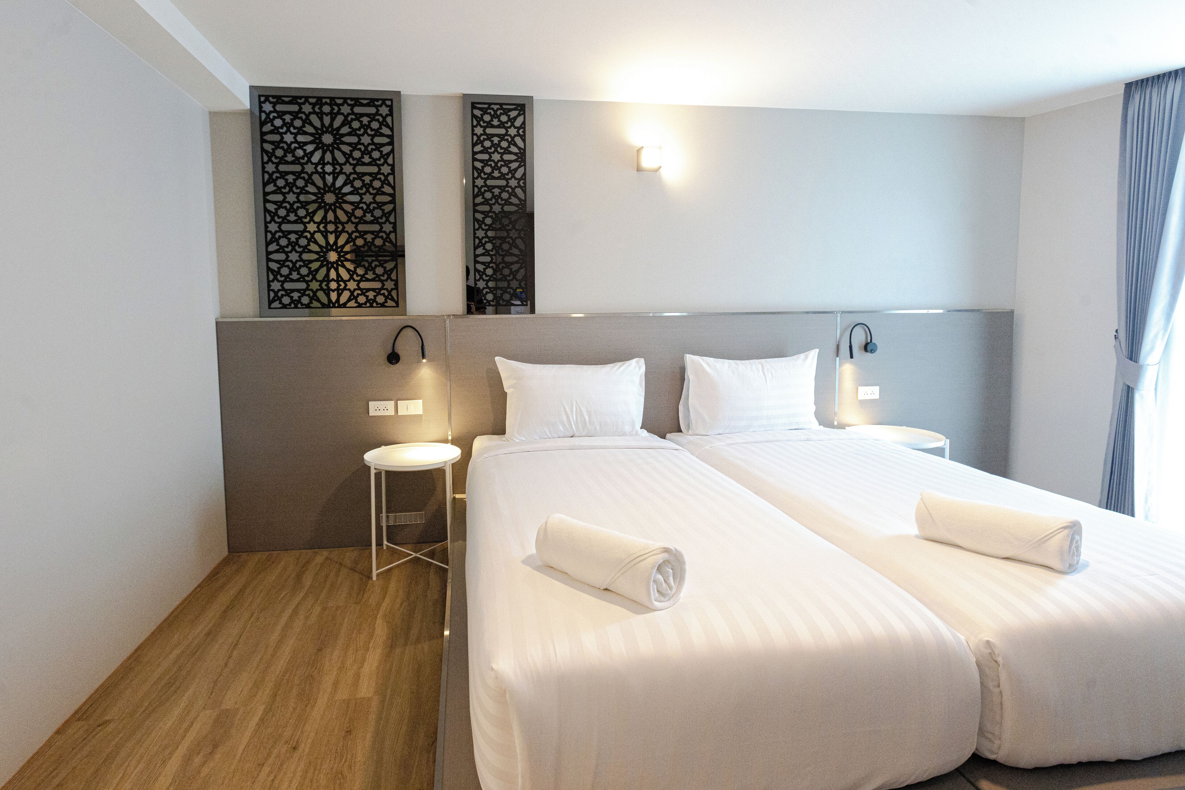 A hotel room with two beds, a small round table, and decorative wall panels.