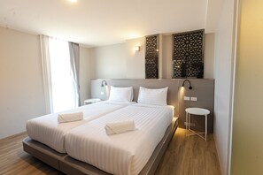 A modern hotel room with a large bed, bedside tables, and a decorative wall panel.