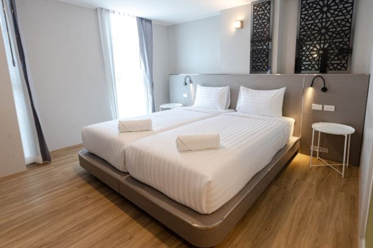 Una habitación de hotel moderna con una cama grande, mesitas de noche y paneles decorativos en la pared.