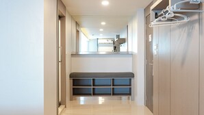 Un pasillo con un banco, perchero y una puerta que da a una habitación.