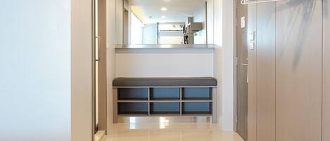 A hallway with a bench, a coat rack, and a door leading to a room.