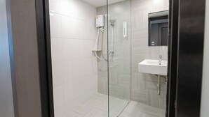 Un baño moderno con cabina de ducha de vidrio, un lavabo blanco y un espejo sobre él.