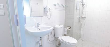 Un baño moderno con lavamanos, inodoro y ducha blancos.