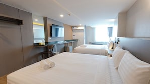 Habitación de hotel con dos camas, un escritorio, un espejo y una ventana con cortinas.