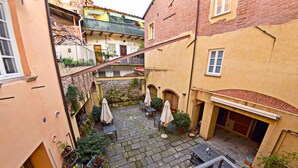 A courtyard with stone paving, outdoor seating, and potted plants.