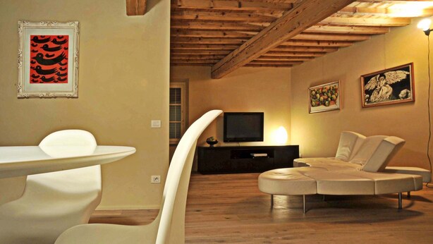 A modern living room with a curved white table, a white sofa, and a flat-screen TV on a wooden stand.