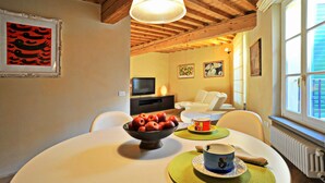 A dining area with a table set for two, a bowl of apples, and a cup on a placemat.