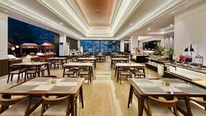 A spacious dining area with multiple tables and chairs, a bar area, and a view of the outside. - The Malioboro Hotel & Conference Center (Yogyakarta)