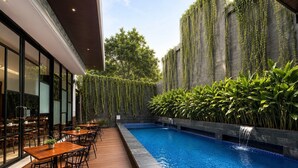A poolside area with a dining setup, a water feature, and a vertical garden wall. - The Malioboro Hotel & Conference Center (Yogyakarta)