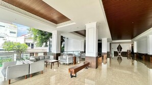 A spacious lobby with a high ceiling, polished marble floors, and a seating area with sofas and a bench. - The Malioboro Hotel & Conference Center (Yogyakarta)