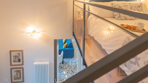 Una habitación de hotel moderna con una cama litera, un sofá azul y una pequeña mesa con pasteles.