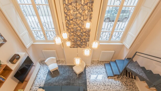 A spacious living area with a sofa, a chair, a TV, and a staircase. - Cinque Giornate 70 Suites (Como)