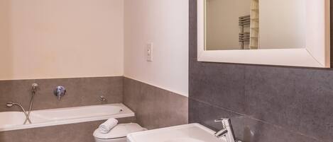 A modern bathroom with a bathtub, a sink, and a toilet.