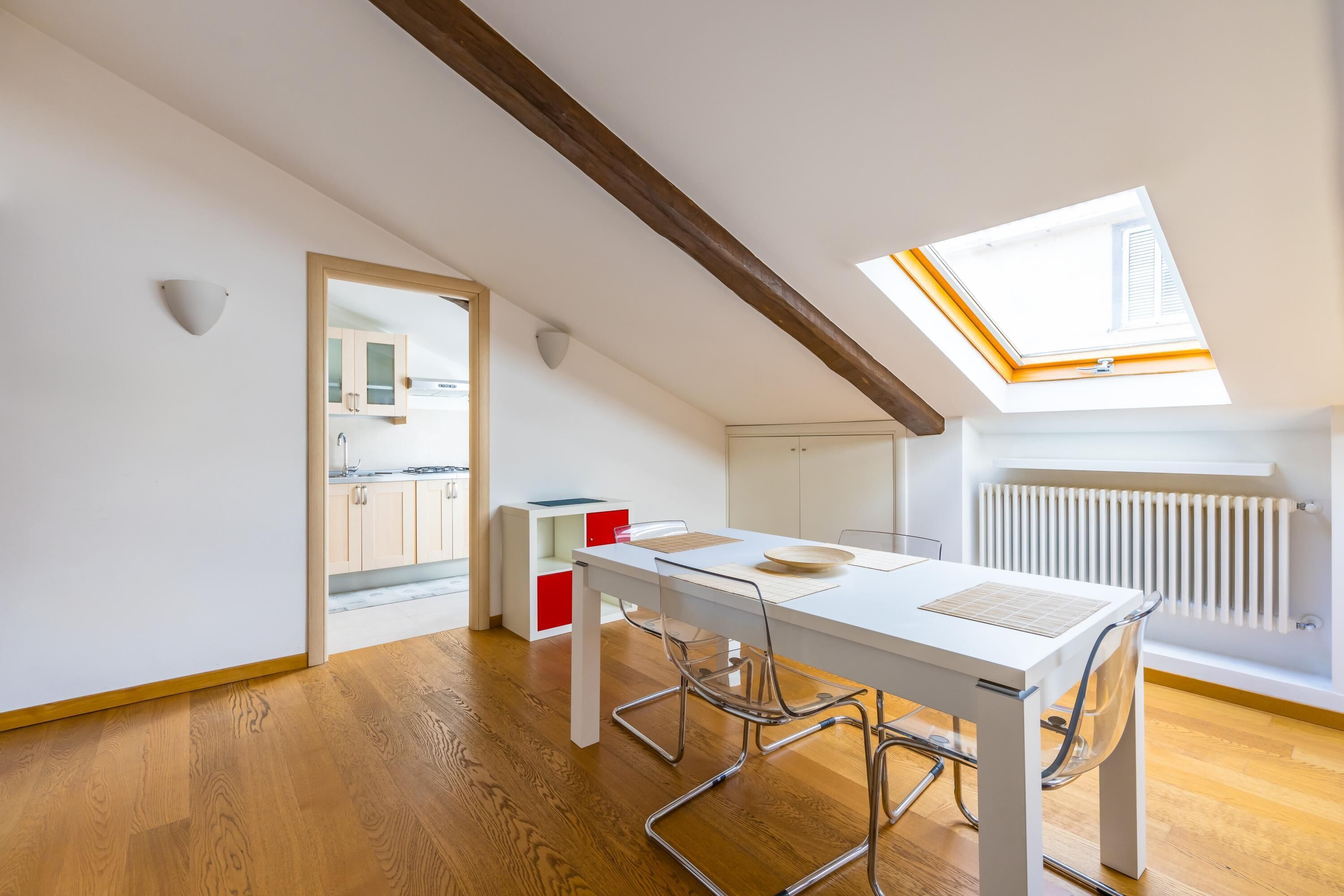 Un espace de vie moderne à aire ouverte, doté d’une verrière, d’un plancher en bois et d’un coin repas avec une table et des chaises blanches.