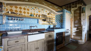 Eine Küche mit einer blau-gelben Fliesenwand, einer Holzauskleidung und einem alten Herd.