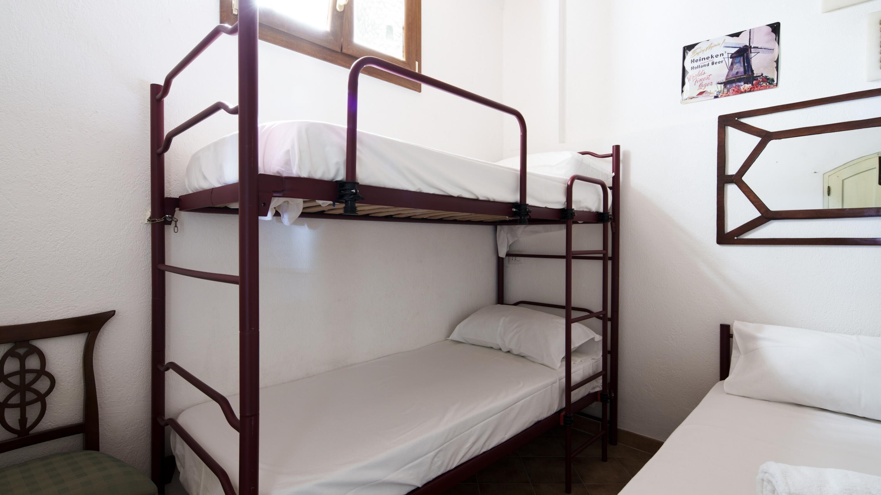 A bunk bed room with a wooden frame, white bedding, and a poster on the wall.