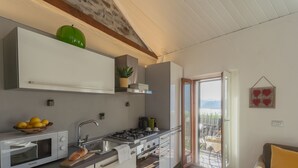 Cozinha moderna com micro-ondas, fogão e pia. Há uma janela com vista para o exterior.